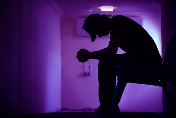 Man sitting in a dark hall with look of despair